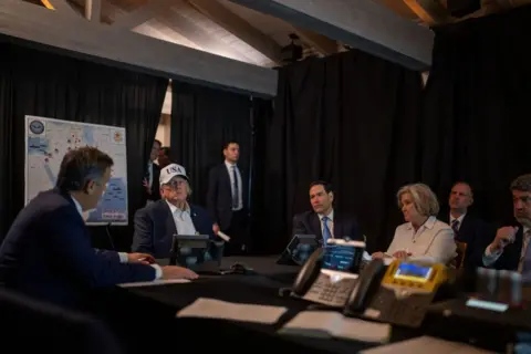 Getty Images President Donald Trump is sat with a white USA cap on listening to Central Intelligence Agency Director John Ratcliffe speaking in foreground and around the table there is US Secretary of State Marco Rubio and White House Chief of Staff Susie Wiles. 