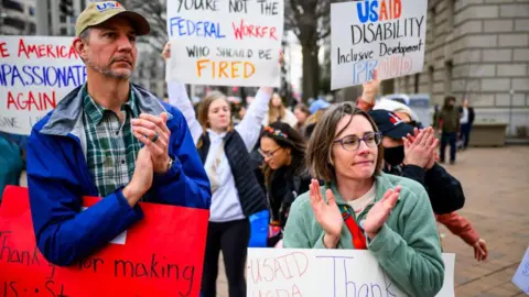 Getty Images Supporters gather with signs and snacks to 'clap out' USAID employees as they clean out their desks at the agency's former offices at the Ronald Reagan Building and International Trade Center on 27 February  in Washington, DC