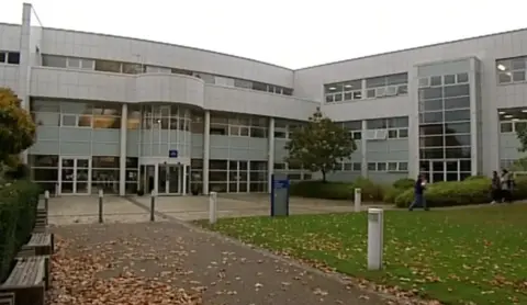 BBC The university of Gloucestershire building, with students walking away from the building. 