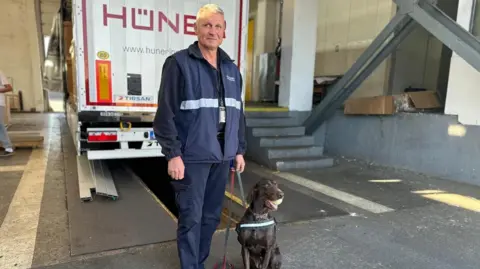 Adele the sniffer dog is with her handler standing in front of a lorry in a customs shed on the Bulgarian border with Turkey