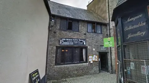 Google A building with exposed brick and lattice windows. The sign above its main window reads 'Old School Coffee House'.  
