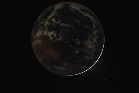 NASA/Reid Wiseman Lights twinkle in the nighttime as the Earth completely occludes the Sun in this image taken from the Orion space capsule.