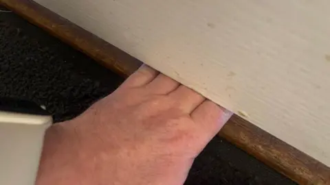 Supplied A hand slid under a white door.