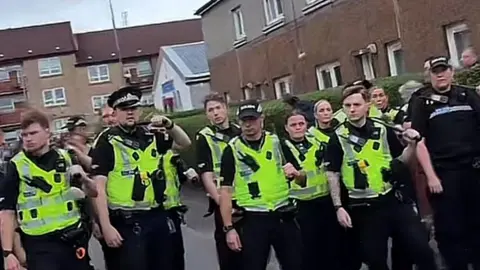 BBC Officers in hi-vis gear standing on a street in Glasgow.