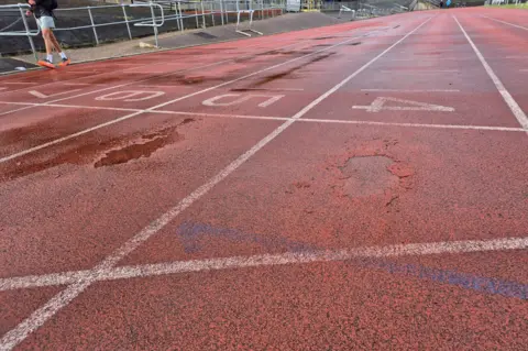 The track at Harvey Hadden Stadium, with numbered lane markings and areas of the track crumbling away.