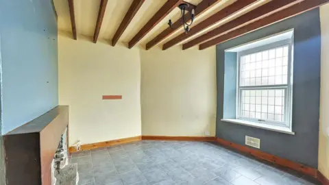 Paul Fosh Auctions An empty lounge with a large window and a fireplace 