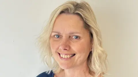 A headshot of Alexander Snow. She has shoulder-length blonde hair and blue eyes and is smiling at the camera against a plain white background.