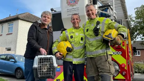 TWFRS The rescued cat, the owner, Micky Longstaff and another fireman