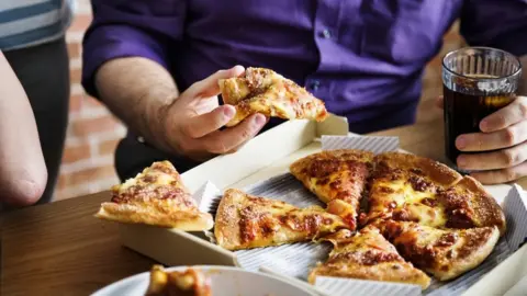 Getty Images Friends eating pizza together