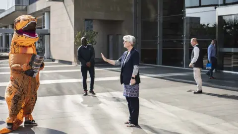 Kim Ludbrook/Shutterstock A member of Standard Bank security personnel ordering an Extinction Rebellion activist wearing a dinosaur to leave the area during an occupation protest in Johannesburg, South Africa, 19 September 2023.