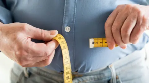 Getty Images Middle-aged man with a tape measure