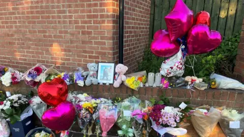 Oli Constable/BBC Floral tributes at the scene 