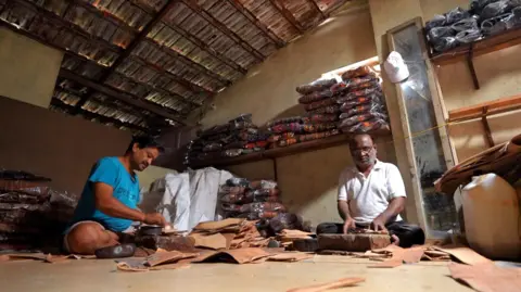 Two artisans make leather sandals at their workshop in Kolhapur, Maharashtra