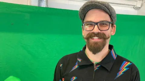 Dom Breadmore in front of a green screen