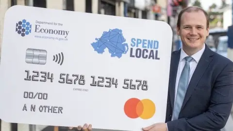 Department for the Economy Gordon Lyons pictured with a Spend Local card
