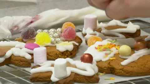 Gingerbread biscuits being decorated with sweets