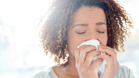 Women with a cold blowing her nose