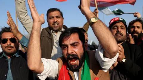 Reuters PTI supporters wearing red and green chanting against vote fraud at a protest on the Peshawar-Islamabad highway on 13 February