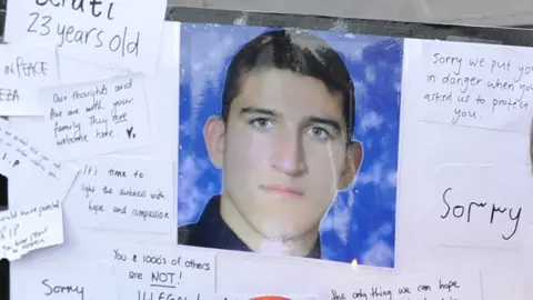 Getty Images People places flowers and cards next to the portrait of Iranian asylum seeker Reza Berati during a candlelight vigil in support of asylum seekers.