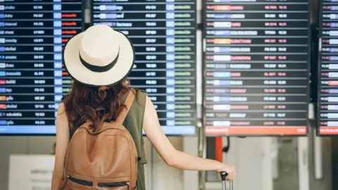 Getty Images Woman looking at airport departure board