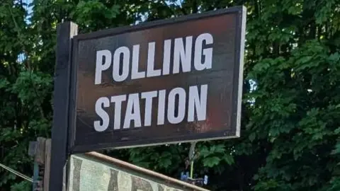 A pub called Larkins Bar, with a black and white polling station sign and signs directing voters on where to go.