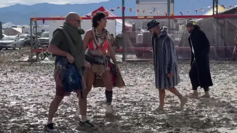 People walk through the mud at Burning Man in Nevada