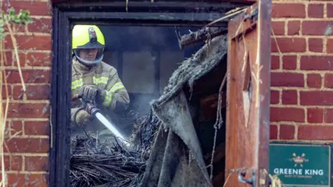 Terry-Harris.com Firefighter tackling hotspots after a pub fire