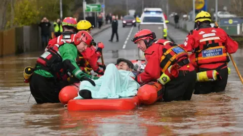 Ben Birchall/PA Wire Rescuers help Peter Morgan in a boat