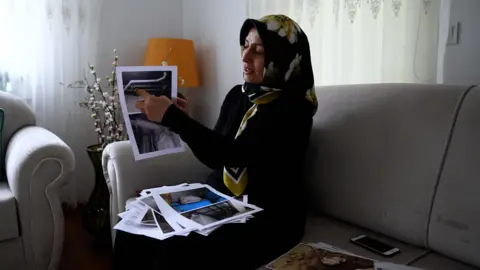Kawoon Khamoosh/BBC Nurgül Göksu shows pictures of the building where her son and his family lived