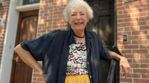 Judy Aleksalza smiling outside of her home