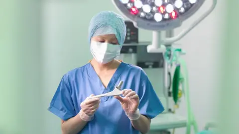 Getty Images Surgeon with artificial hip joint