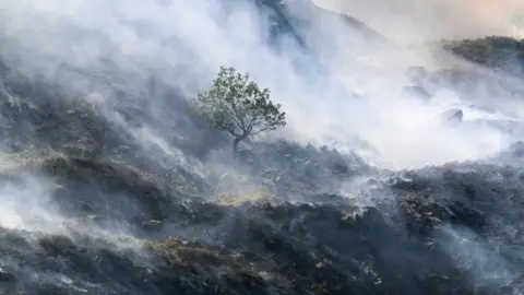 An area of moorland hillside thicky covered in smoke from burning vegetation