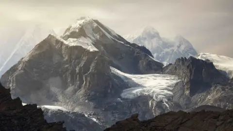 Getty Images Mount Everest's snowy summit surrounded by peaks with snow and bare rock