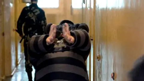 Viasna Prisoner walks handcuffed inside a prison in Minsk in 2006