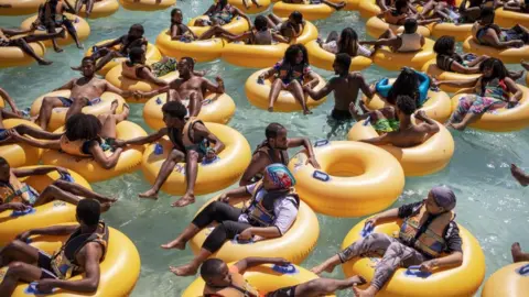 Michele Spatari/AFP Vacationers play with inflatable donuts at a water park in Bishoftu on December 3, 2023. Just 40 kilometres outside Addis Ababa in the Oromia Region, Bishoftu is known for the number of crater lakes and its resorts, which makes it one of the premium leisure spots in the vicinity of the Ethiopian capital.
