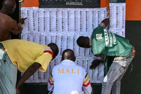 Sia Kambou/AFP Malian nationals look at electoral lists for the referendum on the draft of the new Malian constitution in the district of Adjame, Ivory Coast, 18 June.
