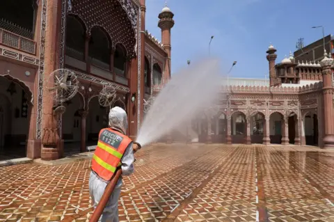 Reuters A worker sprays disinfectant from a hose at the exterior of a mosque