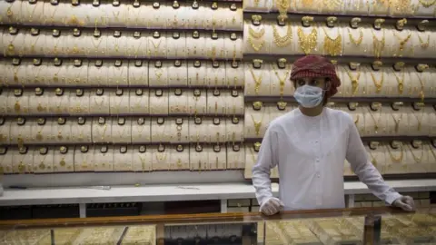EPA A seller wears a protective mask in a gold shop at Dubai Gold Market, Dubai