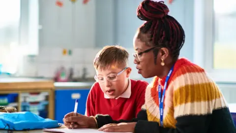 Getty Images Classroom assistant helping student