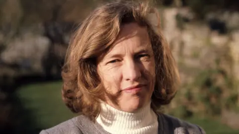 Dr Stella Clarke CBE stood in a garden in 1974