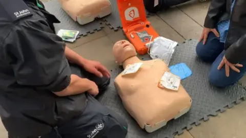 BBC St John Ambulance demonstrating defibrillator