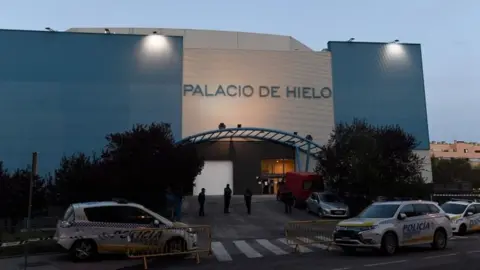 AFP Policemen stand outside the Palacio de Hielo (Ice Palace) shopping mall where an ice rink was turned into a temporary morgue on March 23, 2020 in Madrid to deal with a surge in deaths in the Spanish capital due to the coronavirus