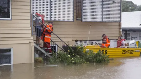 Reuters Emergency workers in a boat help rescue an elderly resident from his home in Rosslea, Townsville