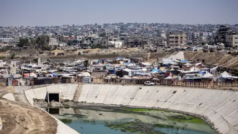 EPA Displaced Palestinians set up their tents next to sewage and a garbage dump on a street in Khan Younis camp in the southern Gaza Strip, 01 August 2024