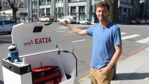 Getty Images Marble co-founder and chief Matthew Delaney prepares a ground-delivery robot to head off with a load outside the start-up's headquarters in San Francisco, California on March 29, 2017.