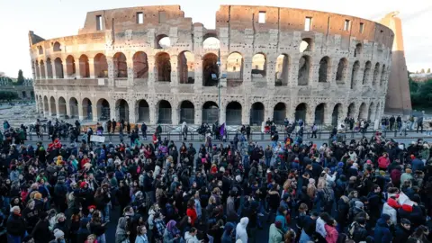 EPA A large crowd of protesters marching past the Colosseum in Rome