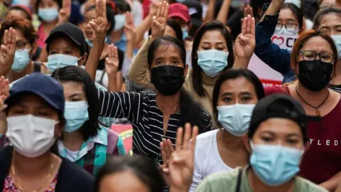 Reuters People flash a three-finger salute as they take part in an anti-coup night protest at Hledan junction in Yangon, Myanmar, March 14, 2021.