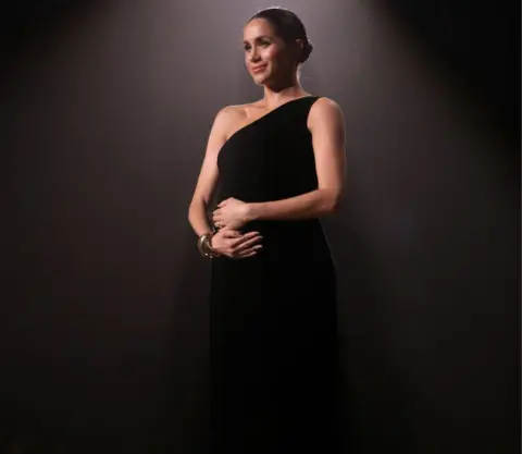 Getty Images Meghan stunned the audience wearing a one-shouldered black Givenchy gown for the occasion