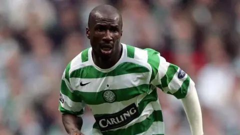 Getty Images Mo Camara in a green-and-white striped Celtic kit, running during a Premiership match.