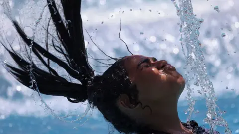 Amr Abdallah Dalsh/Reuters A girl whips her wet hair on 25 July 2023